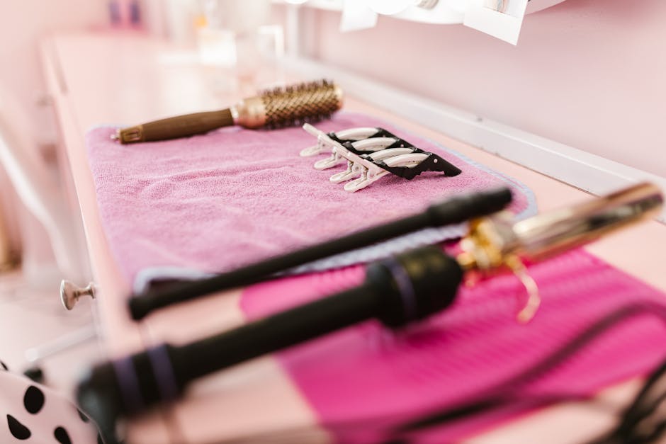 A selection of hair styling tools arranged on a pink towel in a salon setting, ready for use.