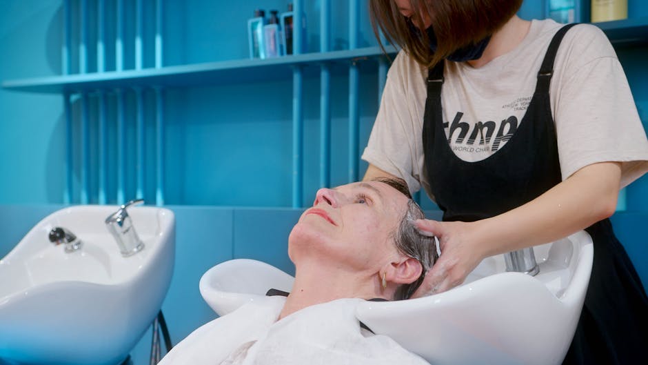 An elderly woman enjoys a professional hair wash at a modern hair salon.